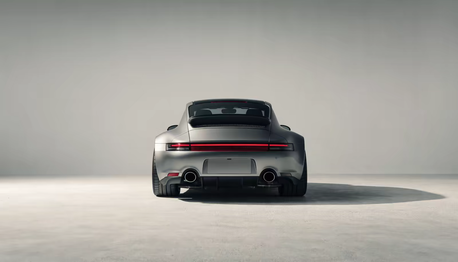 Silver Porsche 911 seen from directly behind in a grey studio