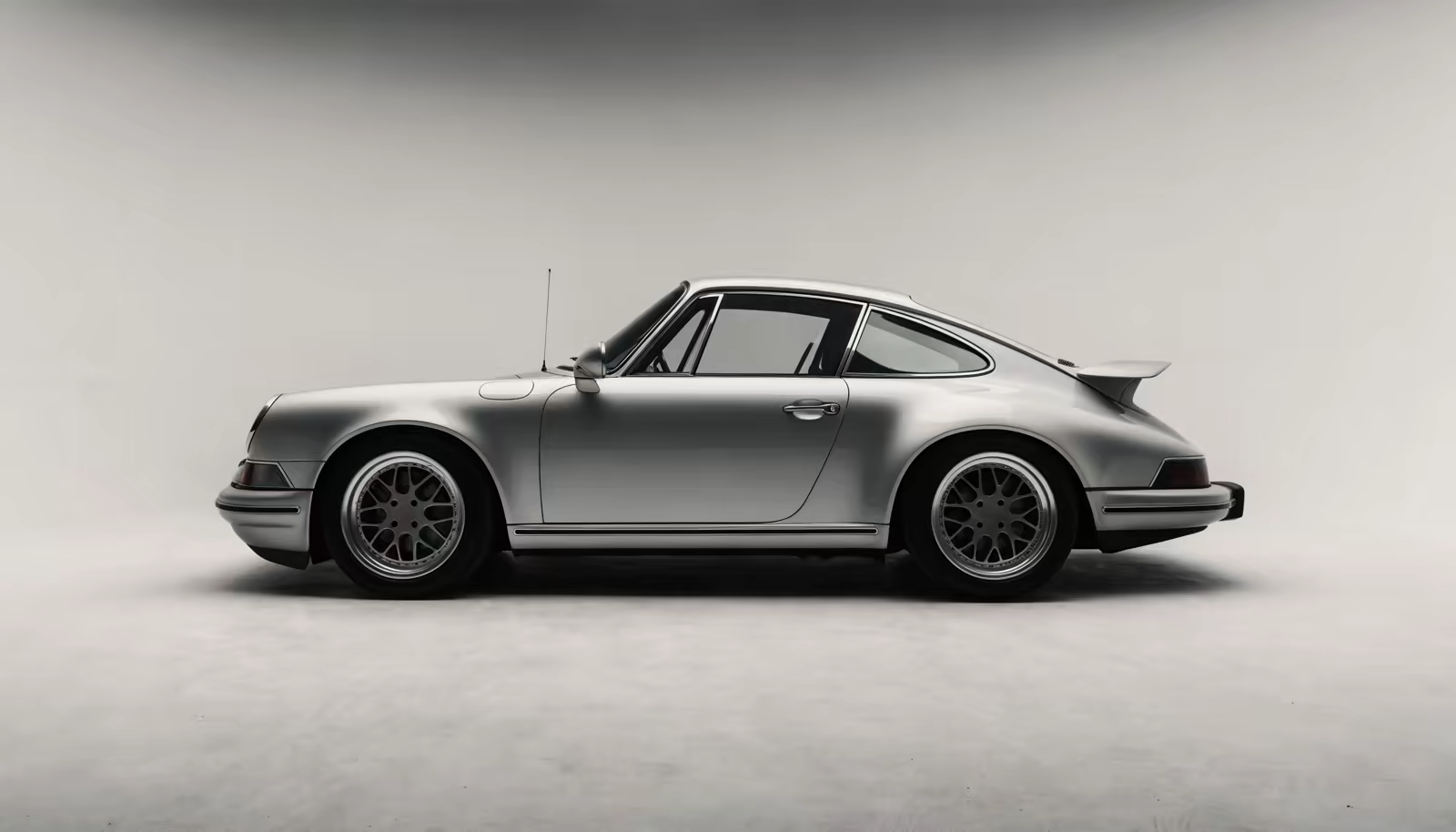 Side profile of a silver Porsche 911 in a grey studio